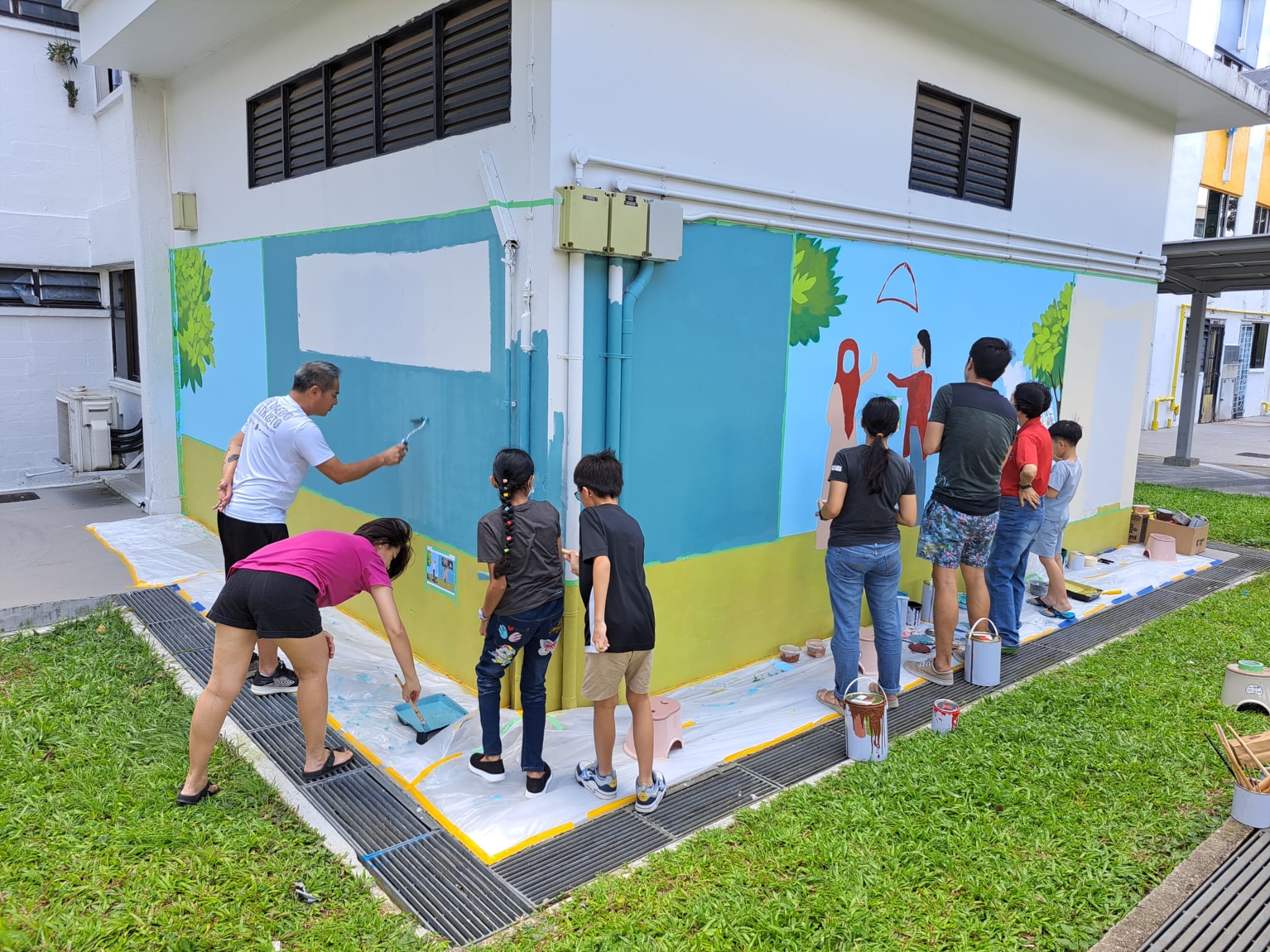 Residents of all ages, from adults to schoolchildren, working together on the mural